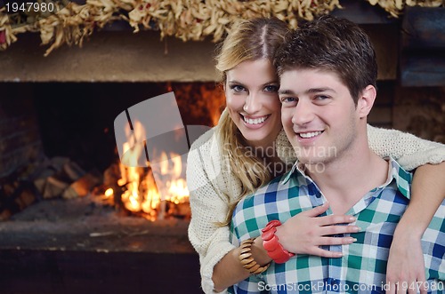 Image of Young romantic couple sitting and relaxing in front of fireplace