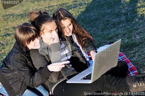 Image of group of teens working on laptop outdoor