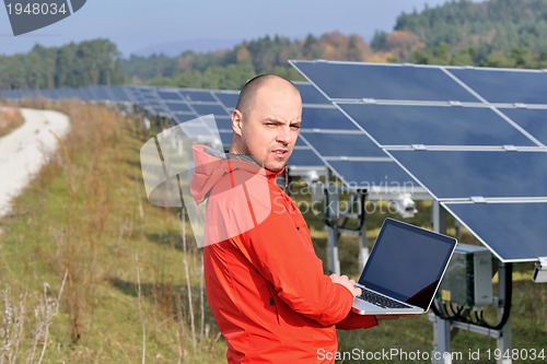 Image of engineer using laptop at solar panels plant field