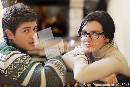 Image of Young romantic couple sitting and relaxing in front of fireplace