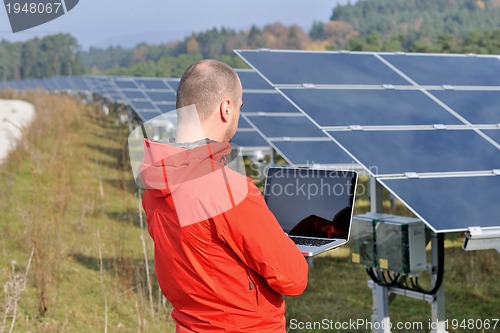 Image of engineer using laptop at solar panels plant field