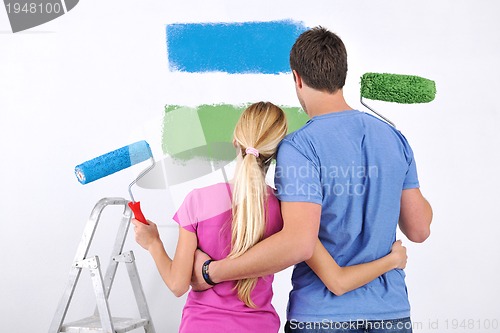 Image of happy couple paint wall at new home