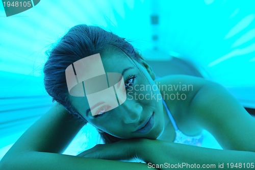 Image of Beautiful young woman tanning in solarium