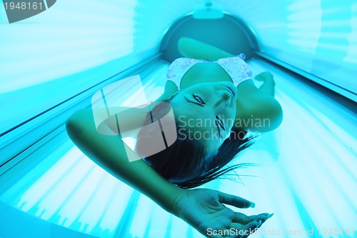 Image of Beautiful young woman tanning in solarium