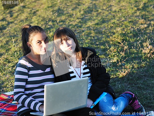 Image of group of teens working on laptop outdoor