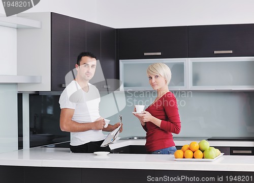 Image of Happy couple reading the newspaper in the kitchen at breakfast
