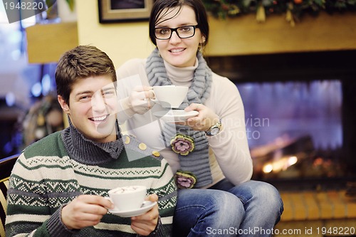 Image of Young romantic couple sitting and relaxing in front of fireplace