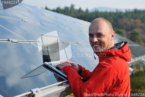 Image of engineer using laptop at solar panels plant field