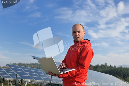 Image of engineer using laptop at solar panels plant field