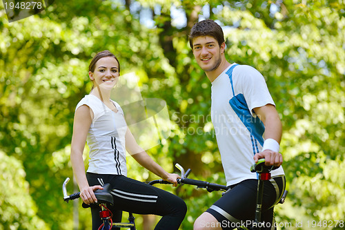 Image of Happy couple riding bicycle outdoors