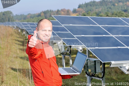 Image of engineer using laptop at solar panels plant field