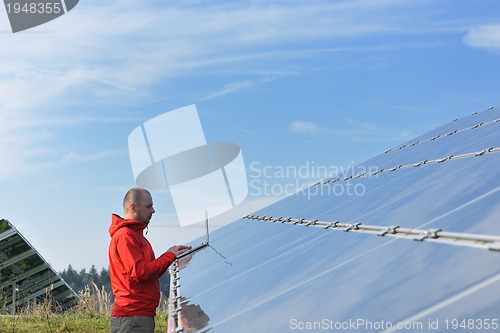 Image of engineer using laptop at solar panels plant field