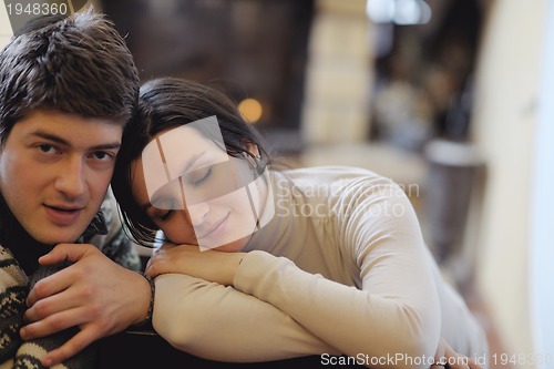 Image of Young romantic couple sitting and relaxing in front of fireplace