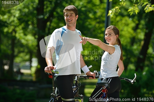 Image of Happy couple riding bicycle outdoors