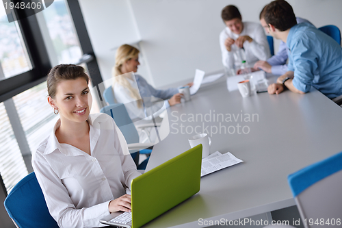 Image of business woman with her staff in background at office