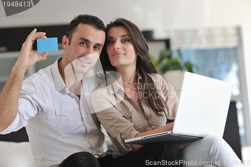 Image of joyful couple relax and work on laptop computer at modern home