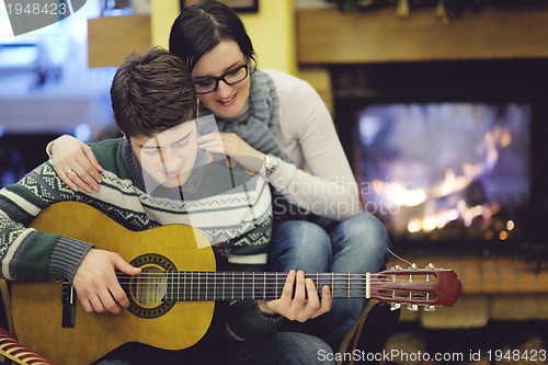 Image of Young romantic couple sitting and relaxing in front of fireplace