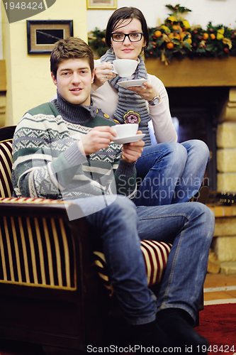 Image of Young romantic couple relax on sofa in front of fireplace at hom