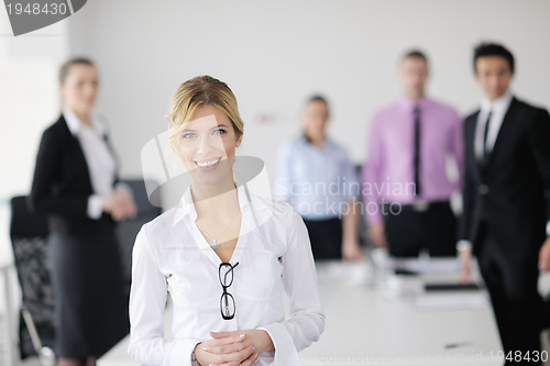 Image of business woman standing with her staff in background