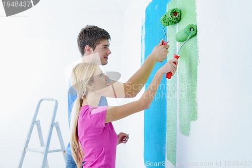 Image of happy couple paint wall at new home