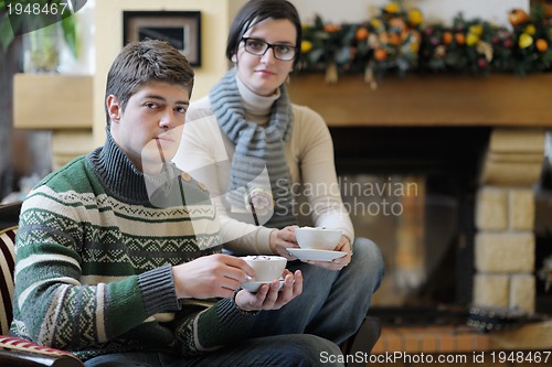 Image of Young romantic couple sitting and relaxing in front of fireplace