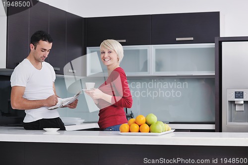 Image of Happy couple reading the newspaper in the kitchen at breakfast
