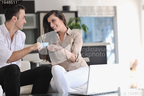 Image of joyful couple relax and work on laptop computer at modern home