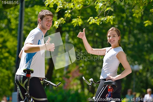 Image of Happy couple riding bicycle outdoors