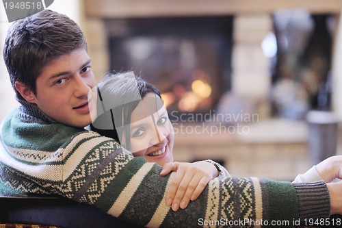 Image of Young romantic couple sitting and relaxing in front of fireplace
