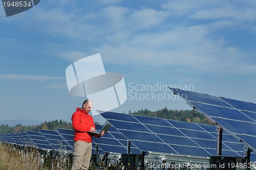 Image of engineer using laptop at solar panels plant field