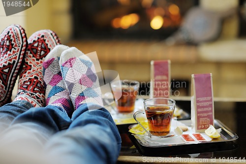 Image of Young romantic couple sitting and relaxing in front of fireplace