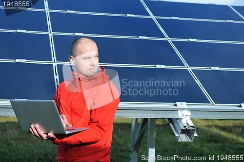 Image of engineer using laptop at solar panels plant field