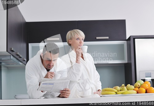 Image of Happy couple reading the newspaper in the kitchen at breakfast