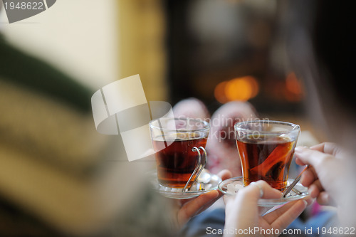 Image of Young romantic couple sitting and relaxing in front of fireplace