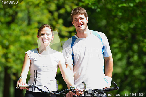 Image of Happy couple riding bicycle outdoors