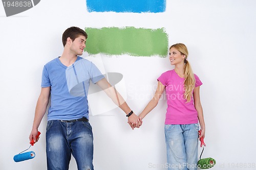 Image of happy couple paint wall at new home