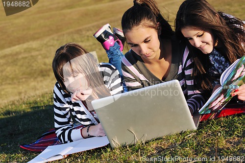 Image of group of teens working on laptop outdoor