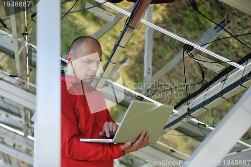 Image of engineer using laptop at solar panels plant field