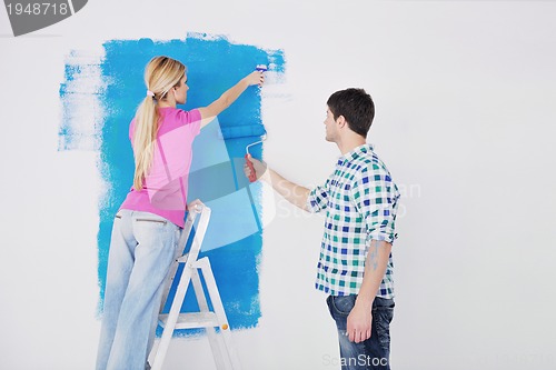 Image of happy couple paint wall at new home