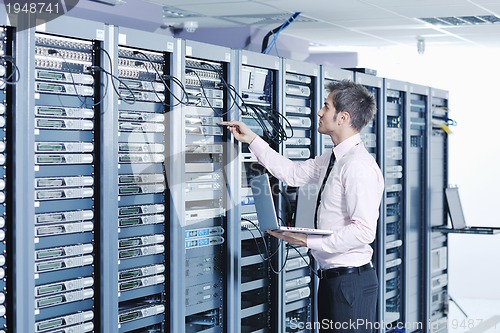 Image of businessman with laptop in network server room