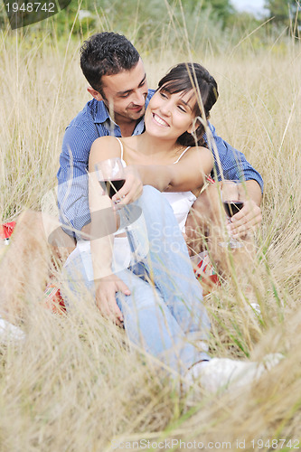 Image of happy couple enjoying countryside picnic in long grass