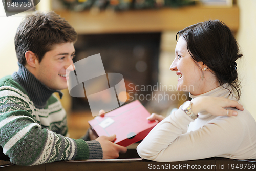 Image of Young romantic couple sitting on sofa in front of fireplace at h