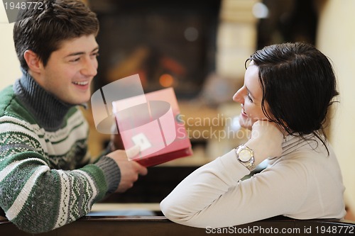 Image of Young romantic couple sitting and relaxing in front of fireplace