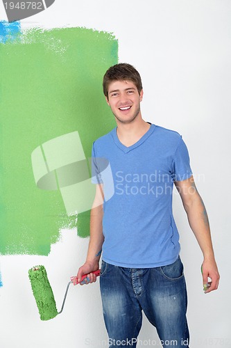 Image of handsome young man paint white wall in color