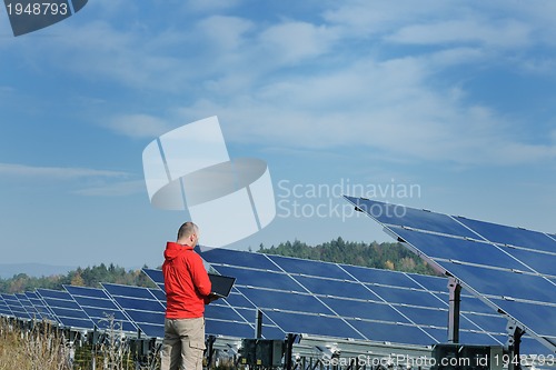 Image of engineer using laptop at solar panels plant field