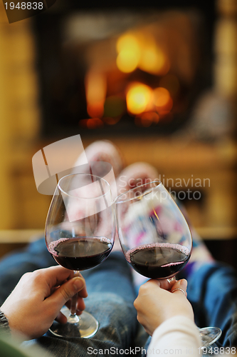 Image of Young romantic couple sitting on sofa in front of fireplace at h