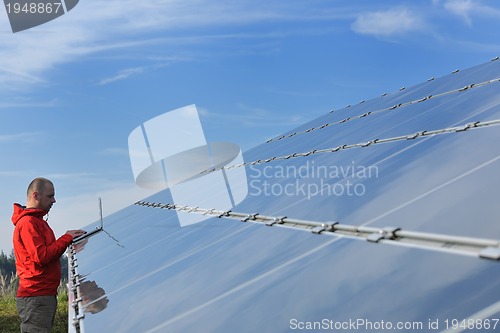 Image of engineer using laptop at solar panels plant field