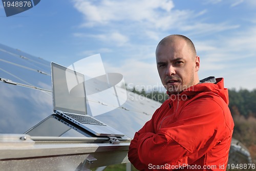 Image of engineer using laptop at solar panels plant field