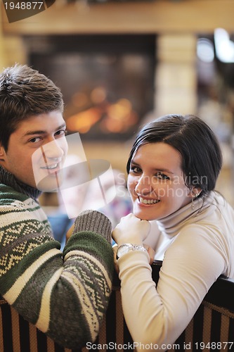 Image of Young romantic couple sitting and relaxing in front of fireplace