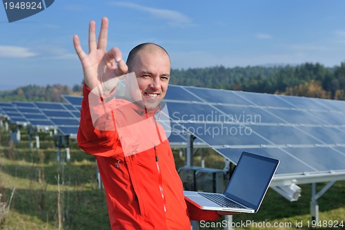 Image of engineer using laptop at solar panels plant field